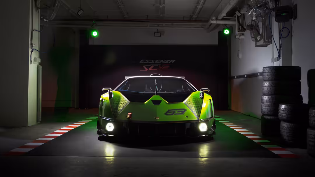 Bright neon green Lamborghini Essenza SCV12 supercar displayed in modern garage with glowing green lights and stacked tires