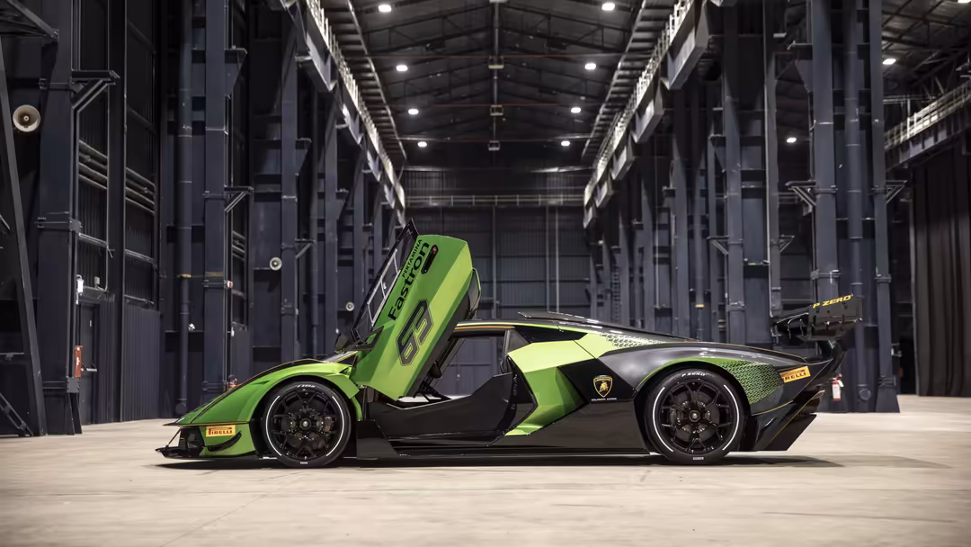 Lime green and black Lamborghini Essenza SCV12 hypercar with open door in industrial warehouse with metal framework and light