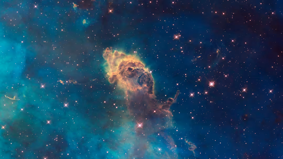 Vibrant Carina Nebula with golden gas clouds, turquoise nebulosity, and scattered stars across deep blue cosmic space