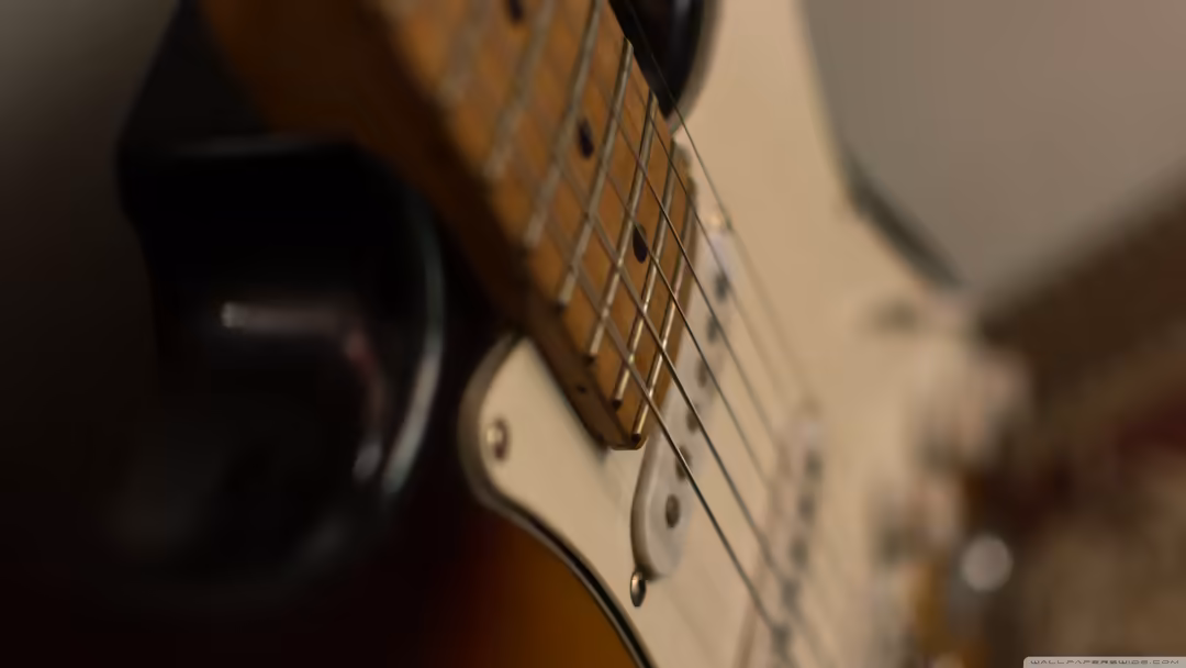Close-up of wooden acoustic guitar headstock with metal strings in warm brown and cream tones