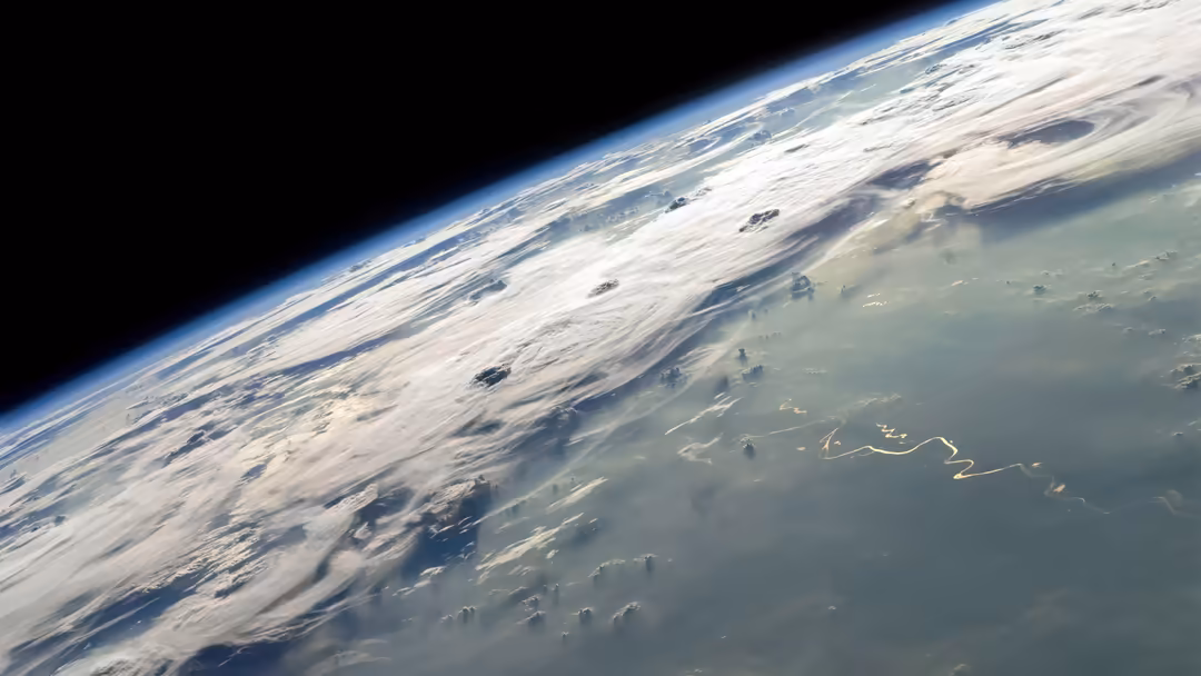 Earth's curved horizon with swirling white clouds and atmospheric layers viewed from space against the black void of the cosm