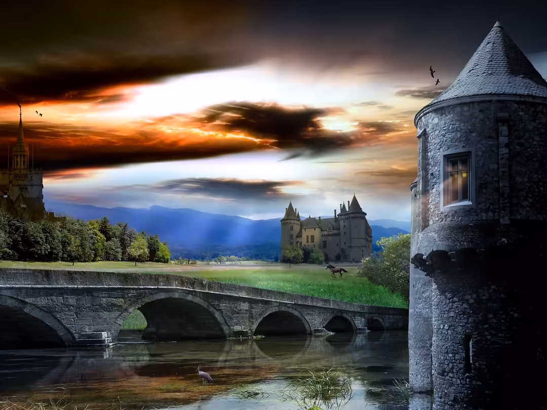 Medieval castle with stone towers overlooking a dramatic sunset sky with golden orange and blue hues, featuring an arched bri