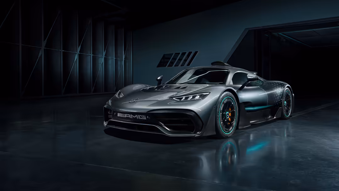 Silver Mercedes-AMG ONE hypercar displayed in a dark industrial garage with moody blue lighting and reflective wet floor