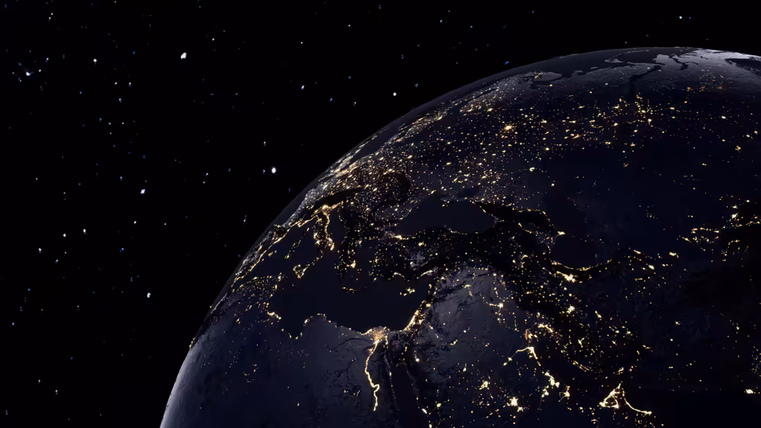 Earth at night from space showing city lights and illuminated regions across continents against dark starry sky