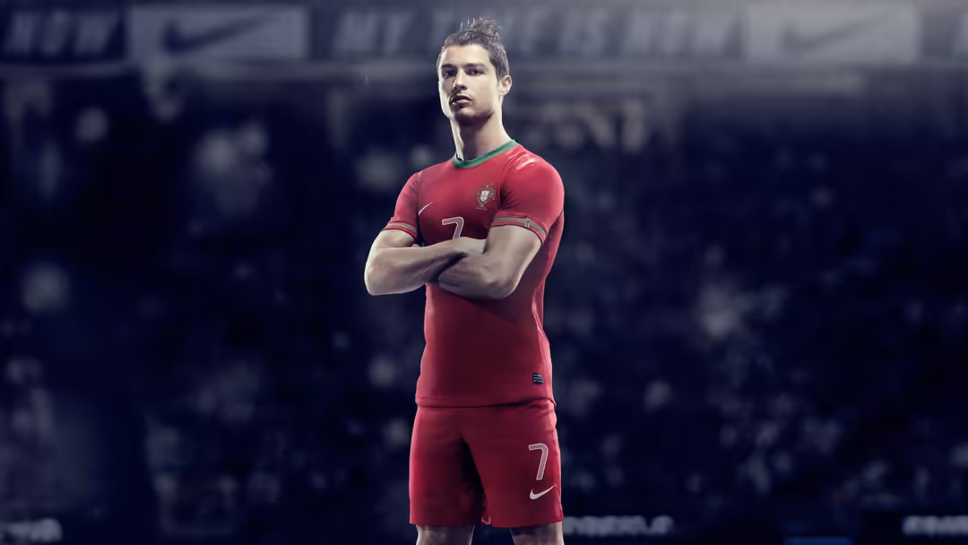 Professional athlete in red national team jersey with arms crossed, confident pose against dark blurred stadium background