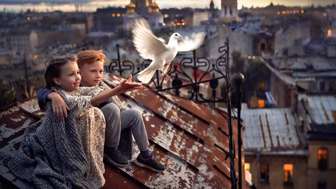 Two children sitting on a rooftop releasing a white dove over a European cityscape at golden hour, symbolizing peace and hope
