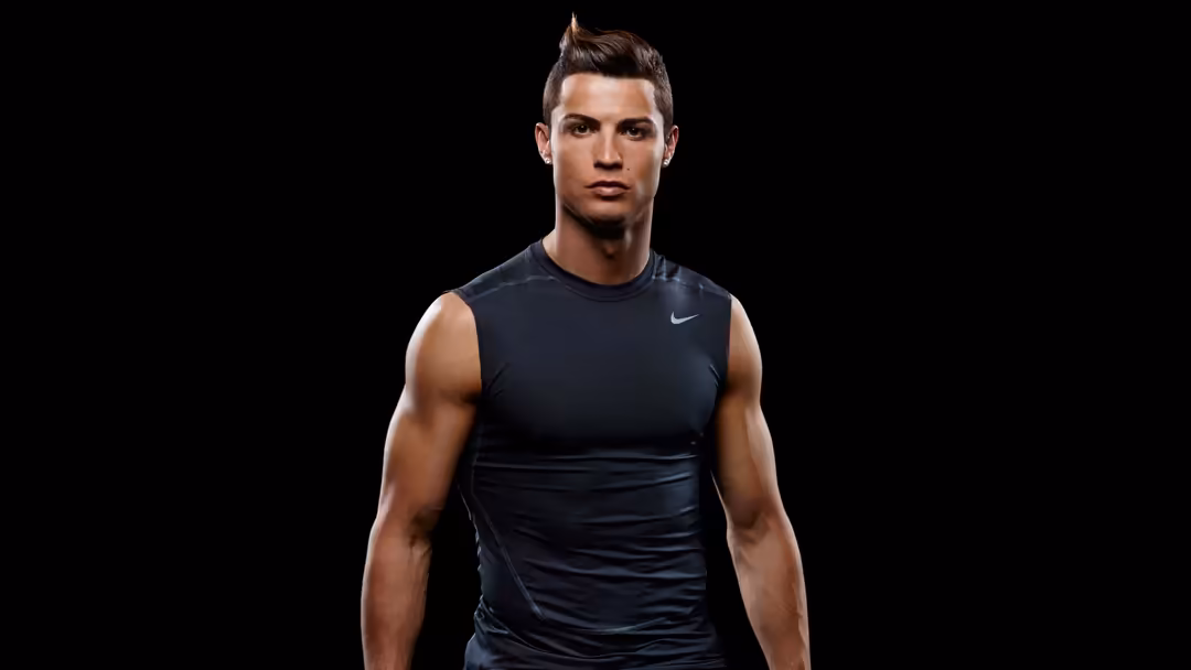 Cristiano Ronaldo in black athletic sleeveless shirt against dark background, professional sports portrait with confident exp