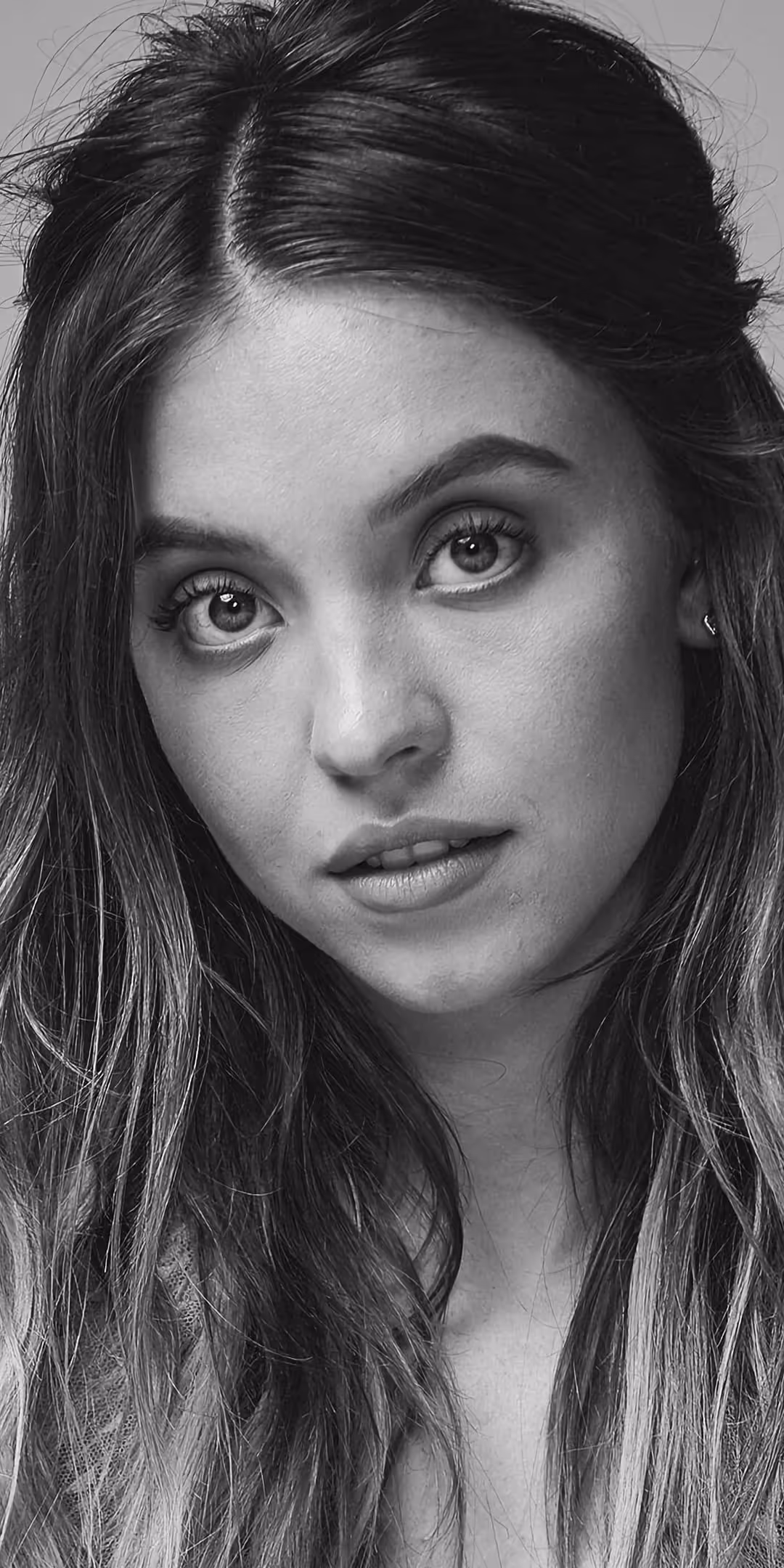 Sydney Sweeney in a striking black and white portrait with dramatic lighting, showcasing expressive eyes and flowing dark hai