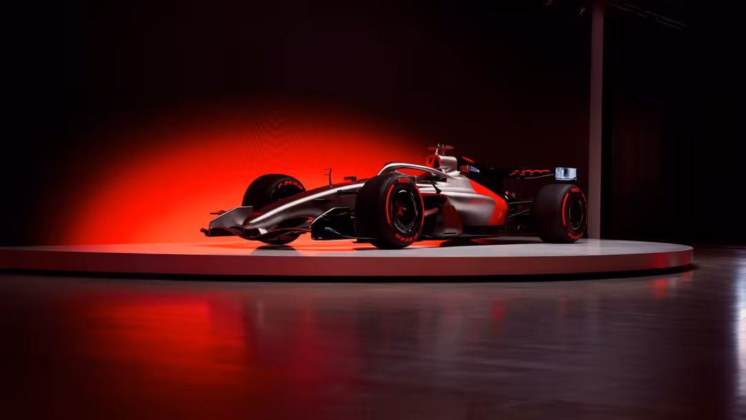 High-performance F1 race car illuminated by dramatic red neon lighting on a dark studio platform with glossy reflective floor