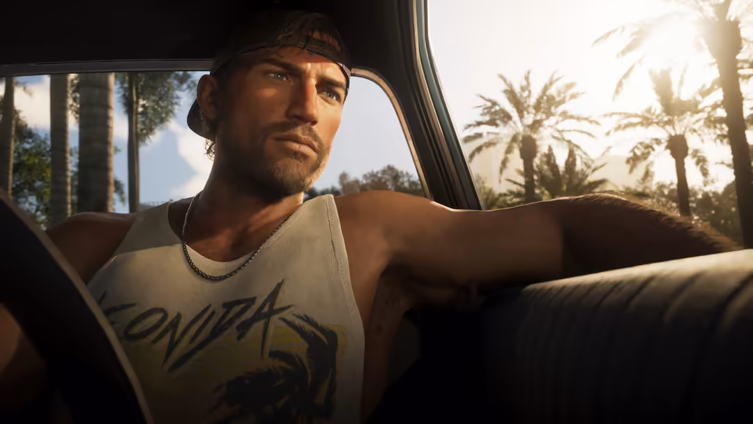 Bearded man in white tank top leaning against car window with palm trees and sunset visible through glass in tropical setting