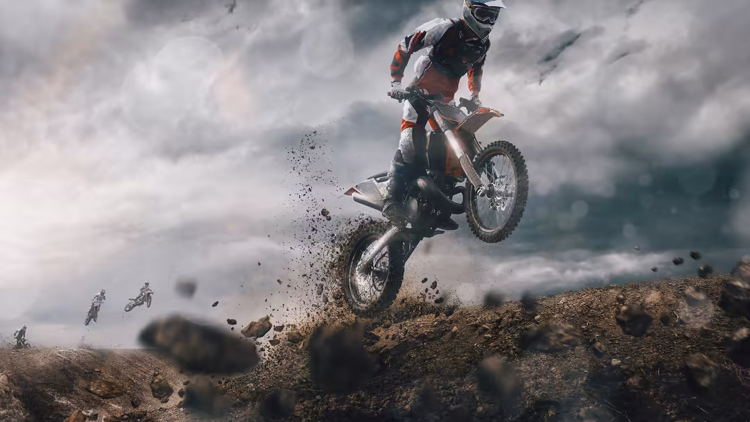 Motocross rider performing high aerial jump on dirt bike with dust clouds against dramatic cloudy sky