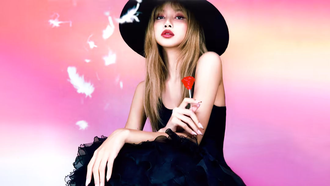 Lisa wearing black wide-brimmed hat and red heart-shaped lollipop against pink gradient background with white floating partic