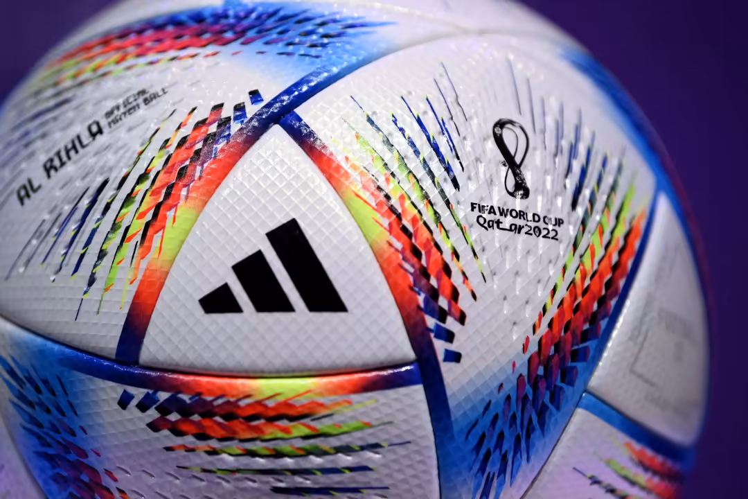 Close-up of a colorful FIFA World Cup soccer ball with red, blue, yellow, and white geometric patterns on purple background