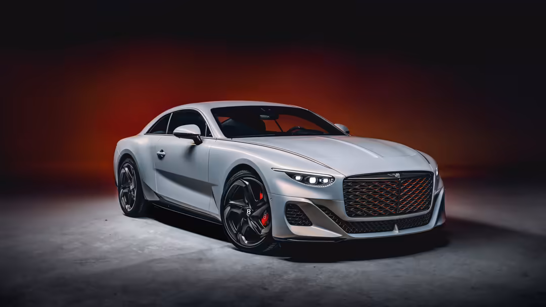 White Bentley Mulliner Batur luxury coupe with dramatic red-orange lighting, sleek design, and striking front grille on dark