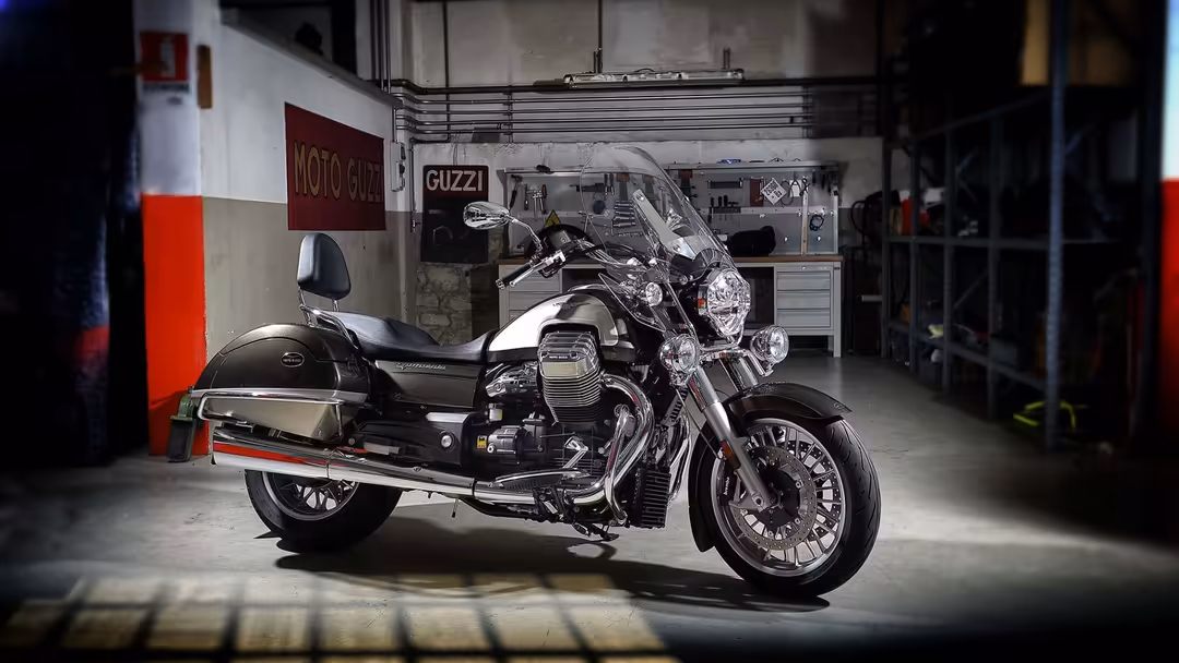 Classic motorcycle with sidecar parked in industrial garage with red and white striped walls and Guzzi signage
