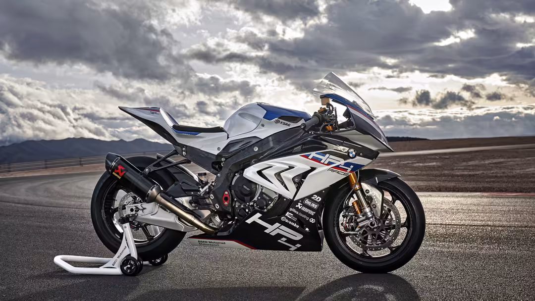 High-performance sportbike with white and black fairing parked on an empty desert road under dramatic cloudy skies with mount