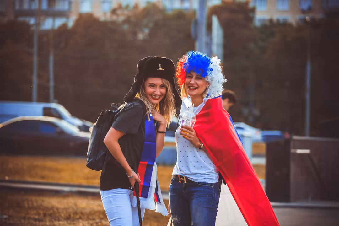 Two women celebrating in outdoor urban setting wearing patriotic FIFA World Cup attire with French flag colors, blue and red