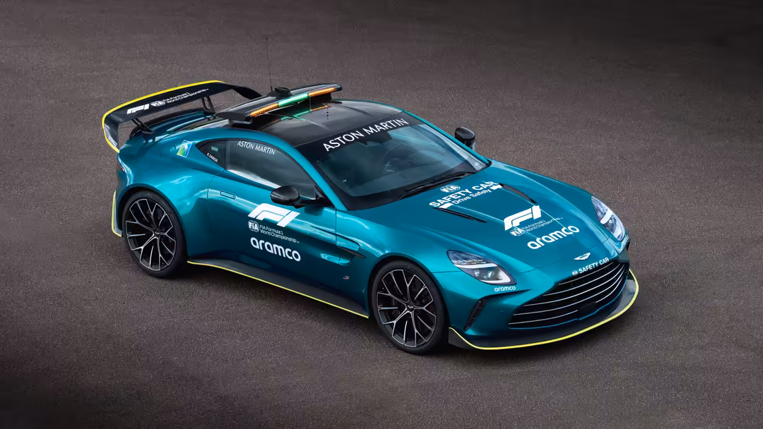 Turquoise Aston Martin F1 race car with yellow accents and aerodynamic design on dark asphalt background