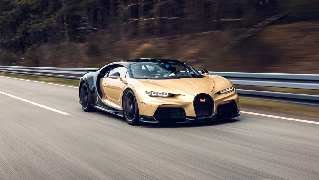 Gold Bugatti Chiron Super Sport hypercar speeding on highway with blurred forest background and motion lines