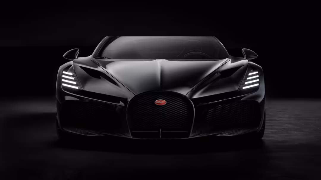Sleek black Bugatti W16 Mistral hypercar front view with glowing LED headlights against dark background
