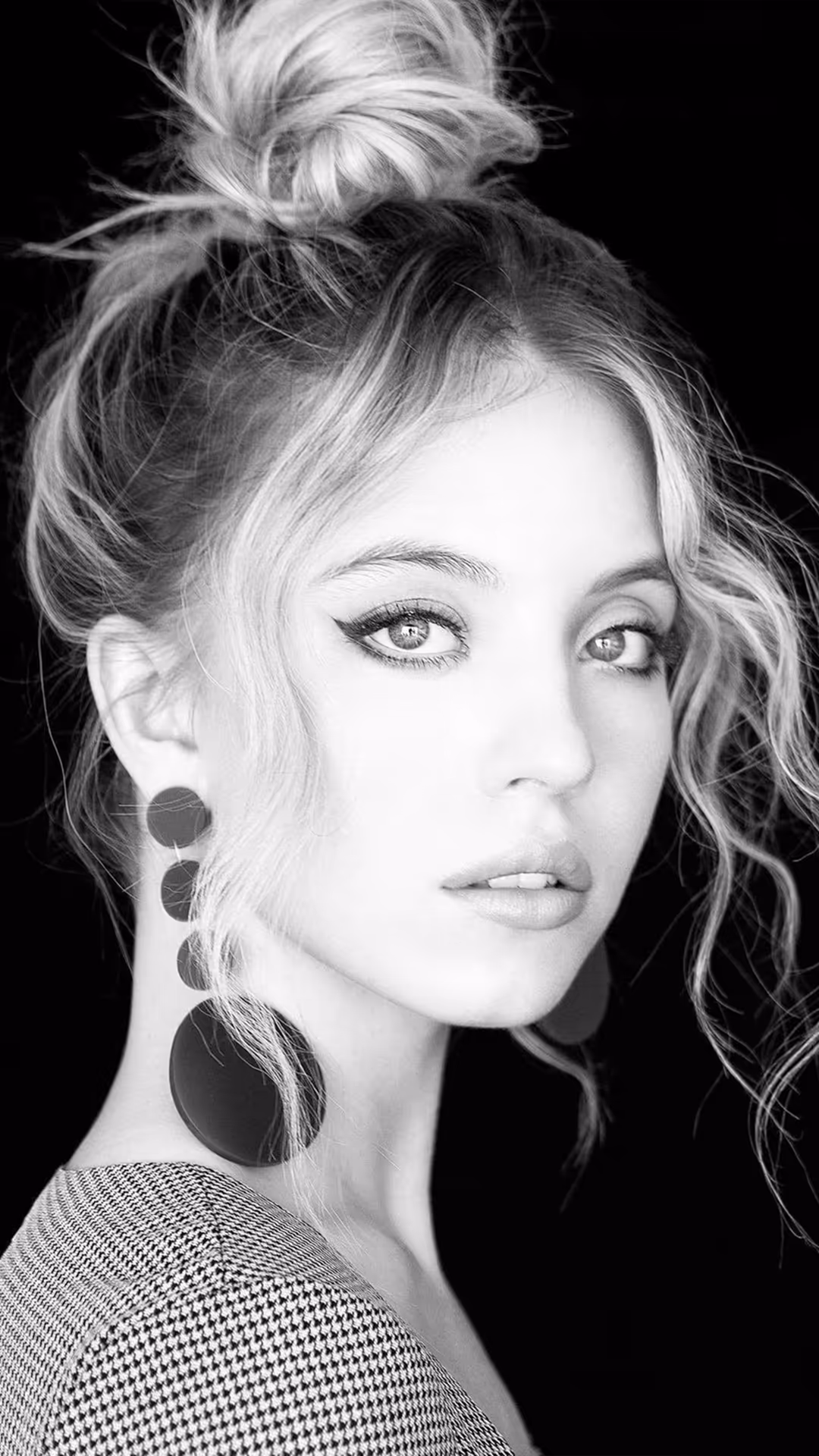 Sydney Sweeney in a striking black and white portrait wearing statement circular earrings with wavy hair styled in an updo ag