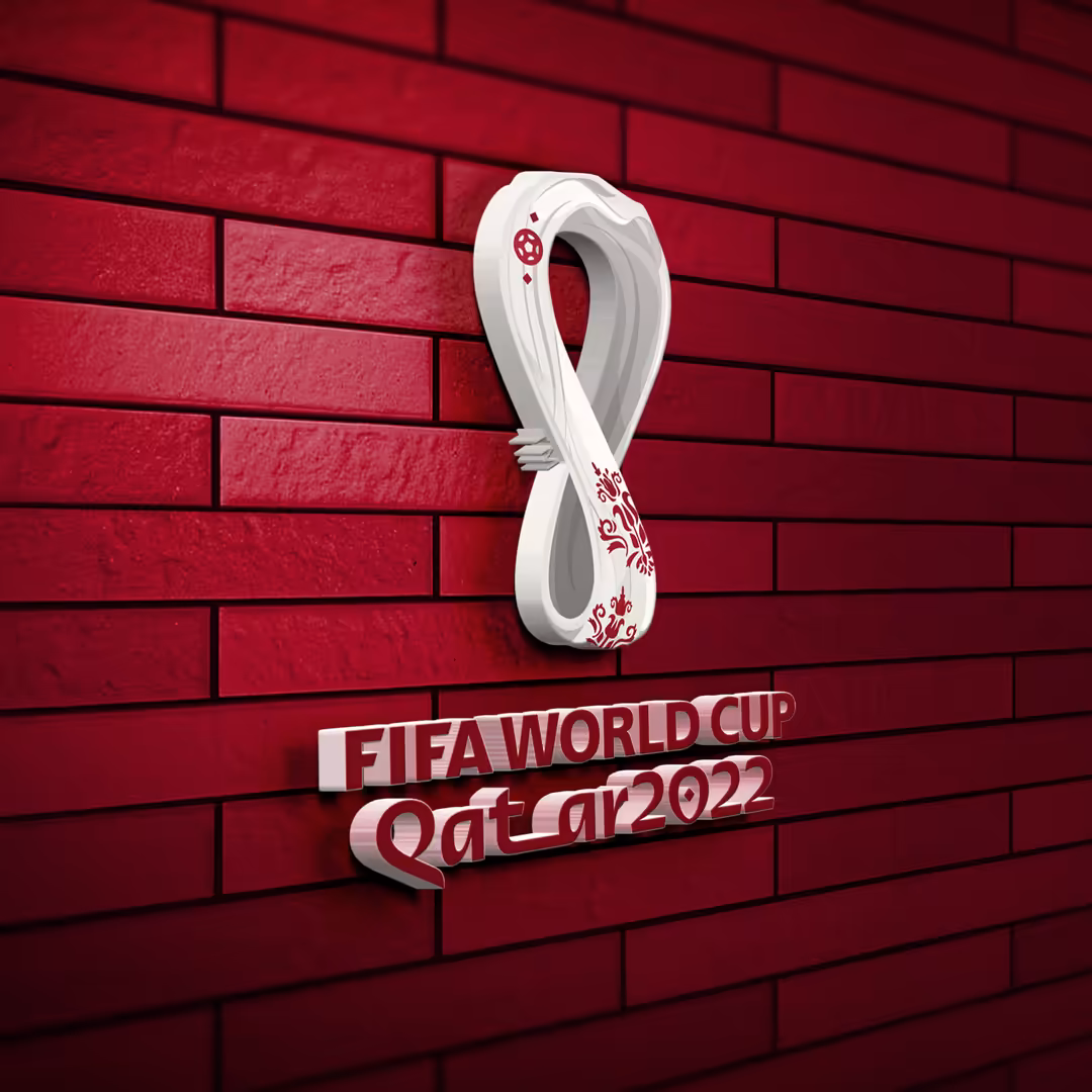 White infinity symbol FIFA World Cup Qatar logo mounted on deep red brick wall with metallic text below
