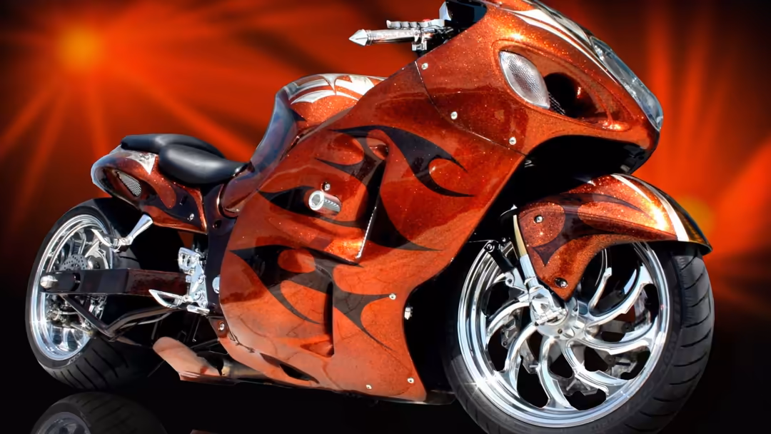 Custom red motorcycle with flame design, chrome wheels, and sleek bodywork against fiery orange background