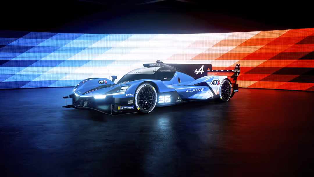 Blue Alpine A424 racing car with number 44 displayed on dark asphalt against red and blue neon backdrop