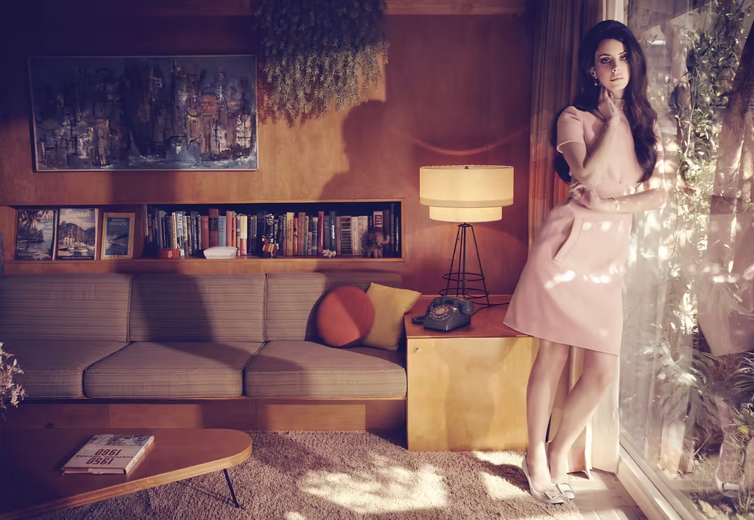 Woman in pink dress standing in retro living room with warm lighting, bookshelves, and vintage furniture aesthetic
