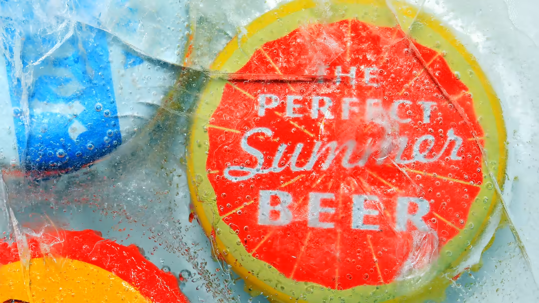 Colorful beer cap submerged in water with vibrant red, yellow, and blue hues, depicting a refreshing summer beverage with con