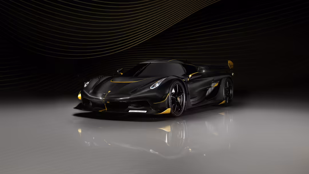 Black Koenigsegg Jesko Odin supercar with gold accents on reflective surface under dramatic lighting