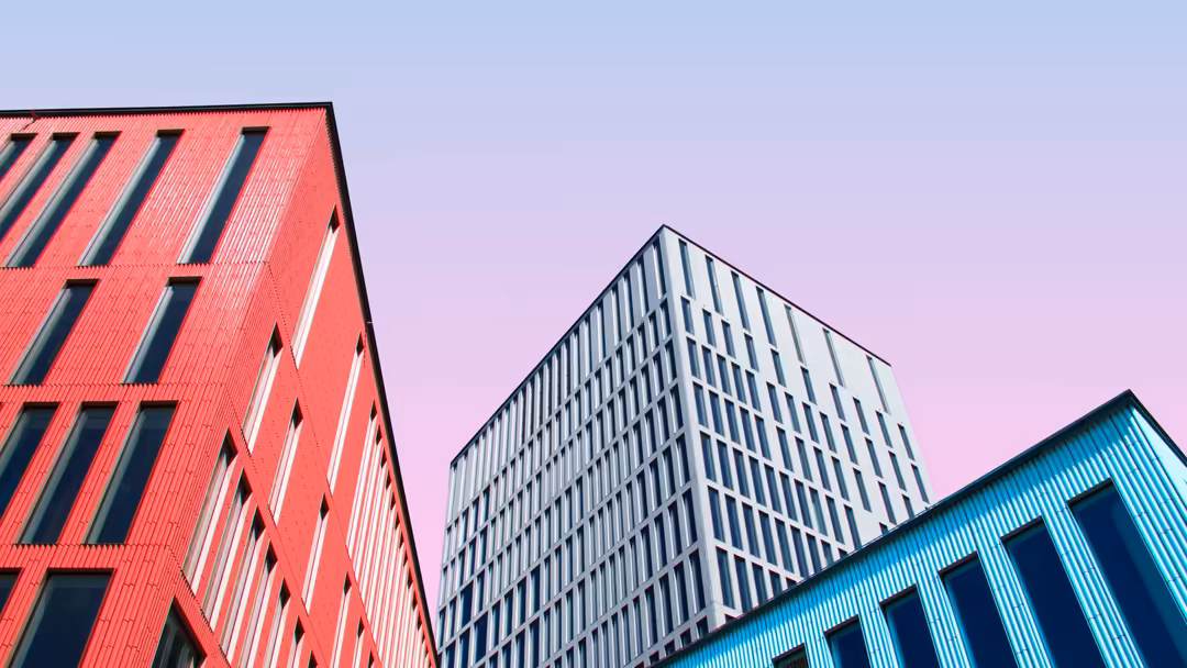 Vibrant modern buildings with red, white, and turquoise facades against a purple sky, showcasing contemporary urban architect