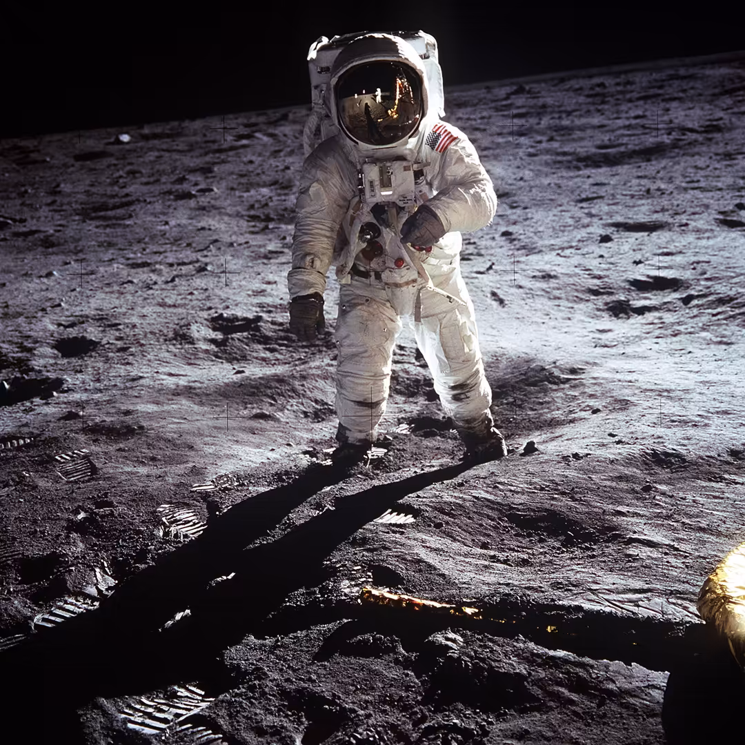 Astronaut in white spacesuit walking on the moon's surface with rocky terrain and black sky in background