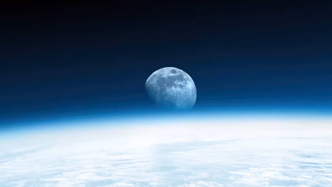 Full moon rising above Earth's horizon with blue atmosphere and white clouds visible below in space