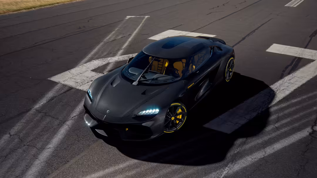 Black Koenigsegg Gemera hypercar with gold accents parked on race track with white lane markings