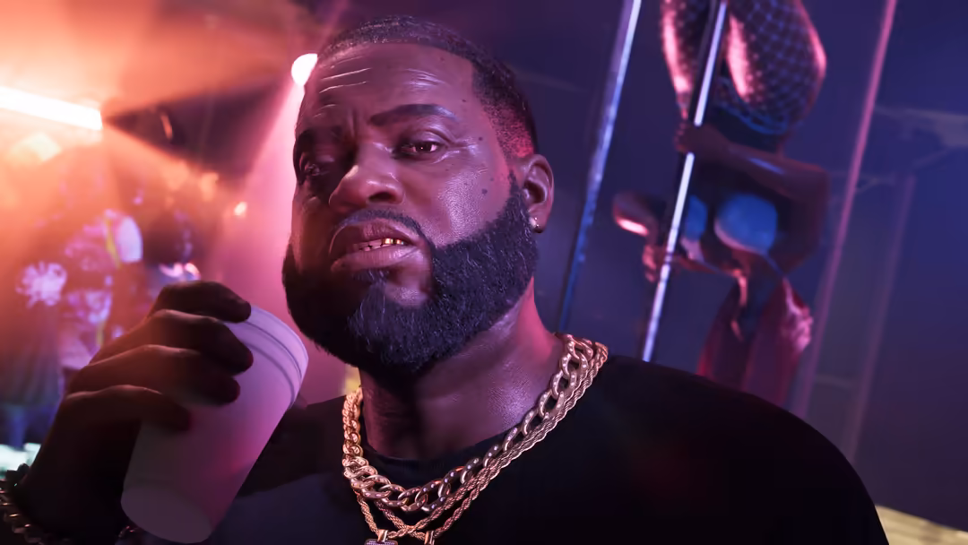 Man with beard wearing gold chain in neon-lit room with pink and blue lighting, holding microphone in GTA VI style setting