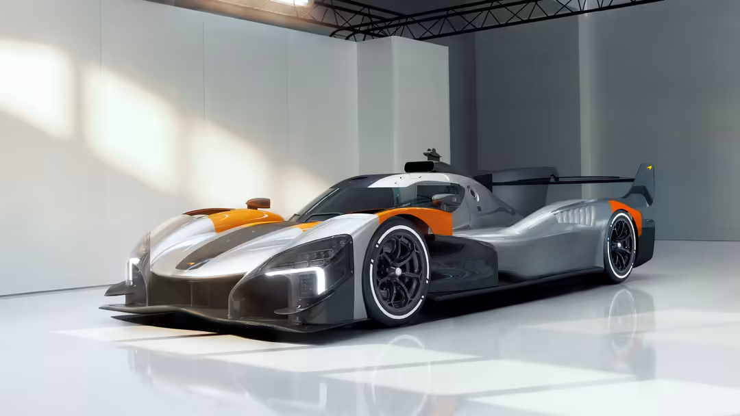 McLaren MCL-HY GTR hypercar displayed in modern white garage with dramatic lighting, featuring orange and silver racing desig