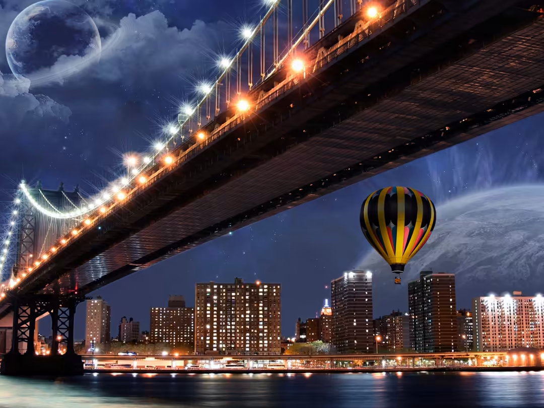 Yellow and black striped hot air balloon floating over illuminated city skyline beneath a glowing suspension bridge at night