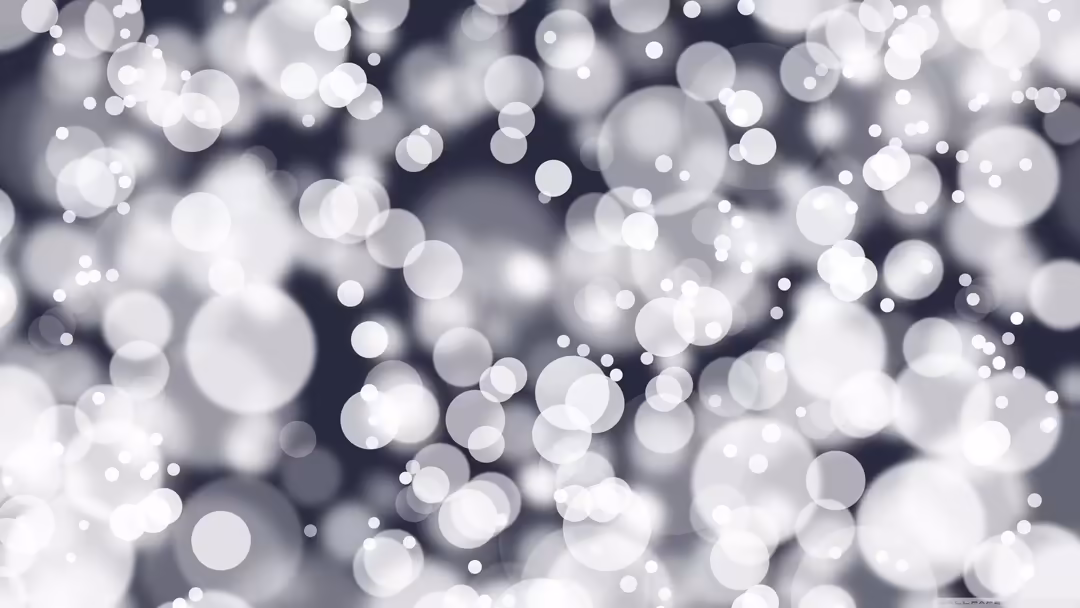 Soft white and gray bokeh light particles floating against a dark blurred background, creating a peaceful and ethereal atmosp