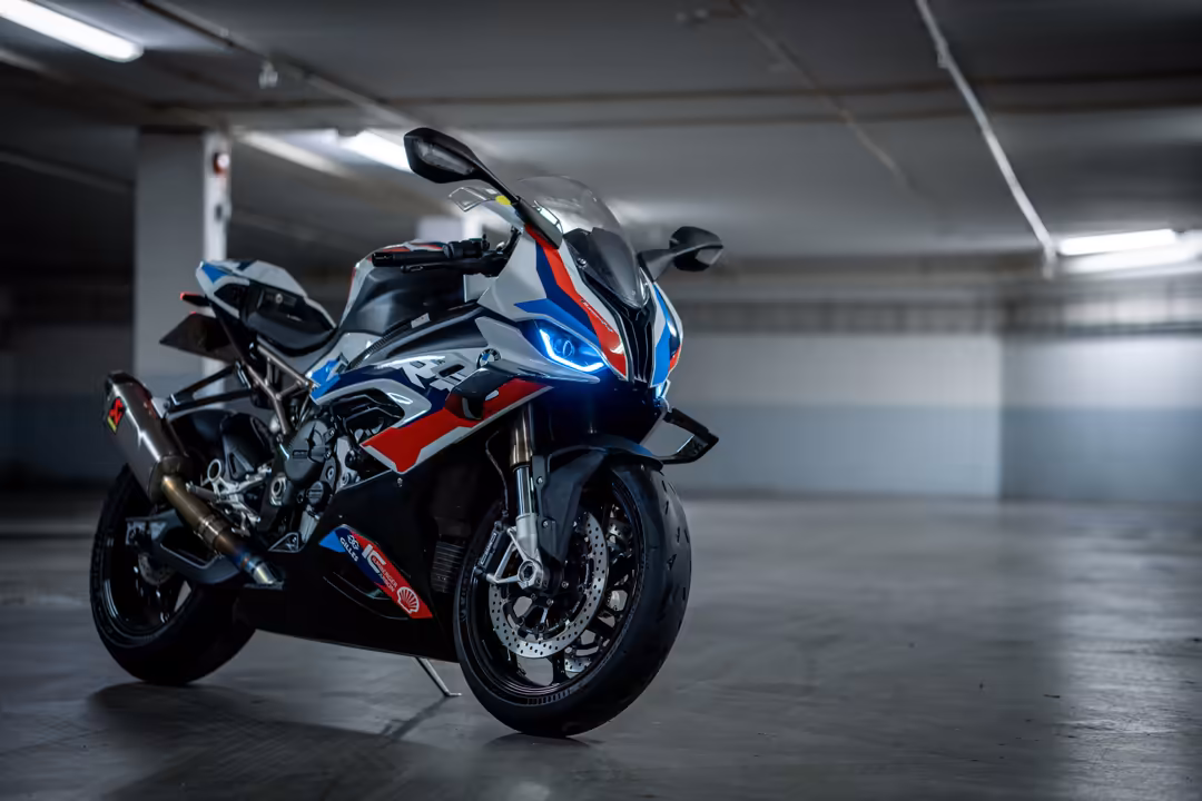 High-performance sport bike with red and blue fairing parked in industrial garage with bright overhead lighting