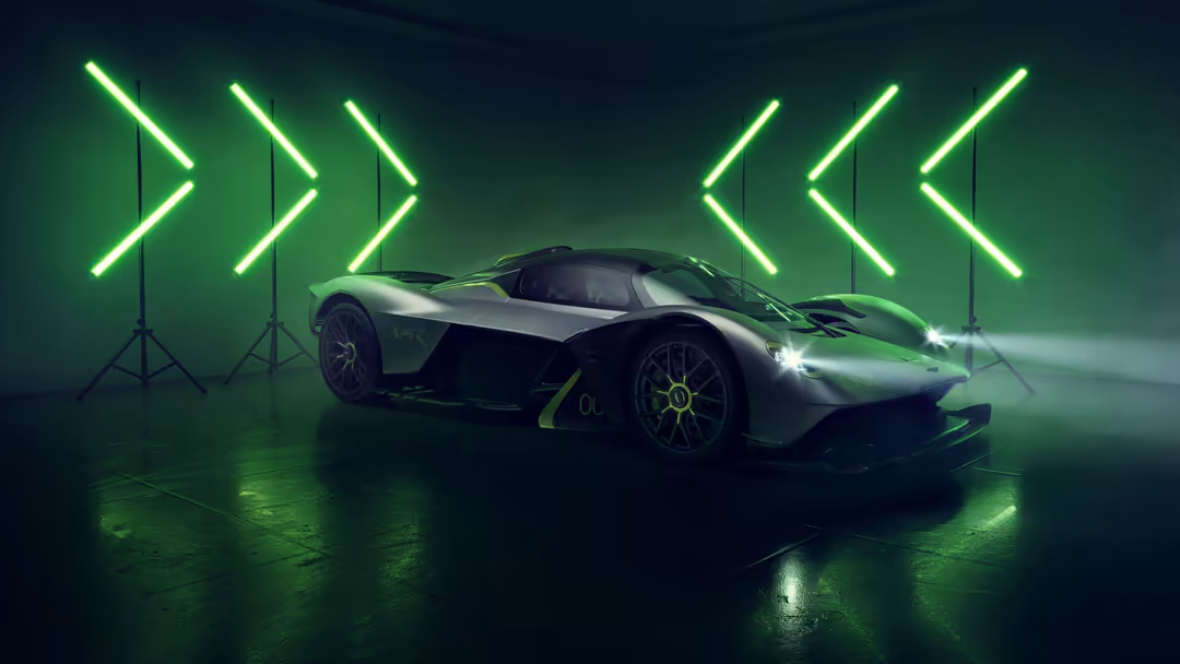 Sleek Aston Martin Valkyrie AMR Pro sports car illuminated by bright green neon arrow lights on wet ground in futuristic sett