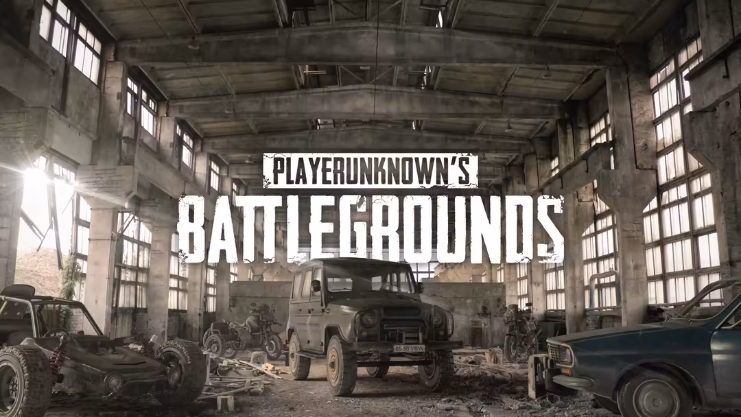 Abandoned industrial warehouse with rusted vehicles and PUBG Battlegrounds logo displayed prominently on weathered concrete w
