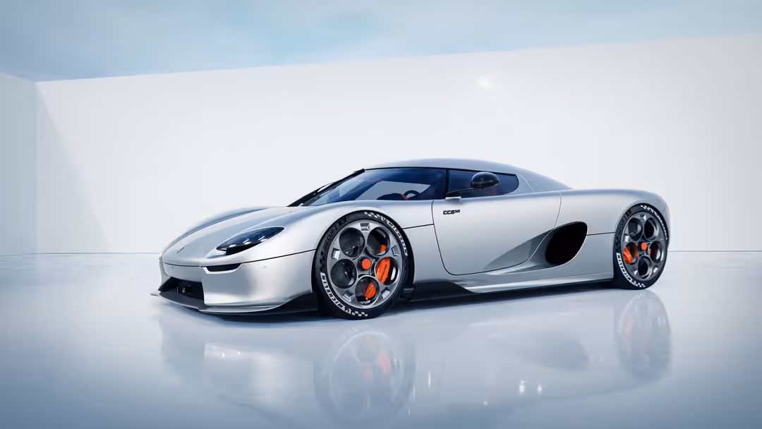 Silver Koenigsegg CC850 supercar with red accents on wheels, displayed in minimalist white studio setting with reflective flo
