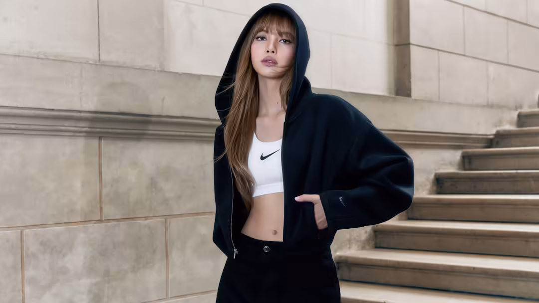 Girl in black zip hoodie and white crop top standing against concrete steps in urban setting with cool confident pose