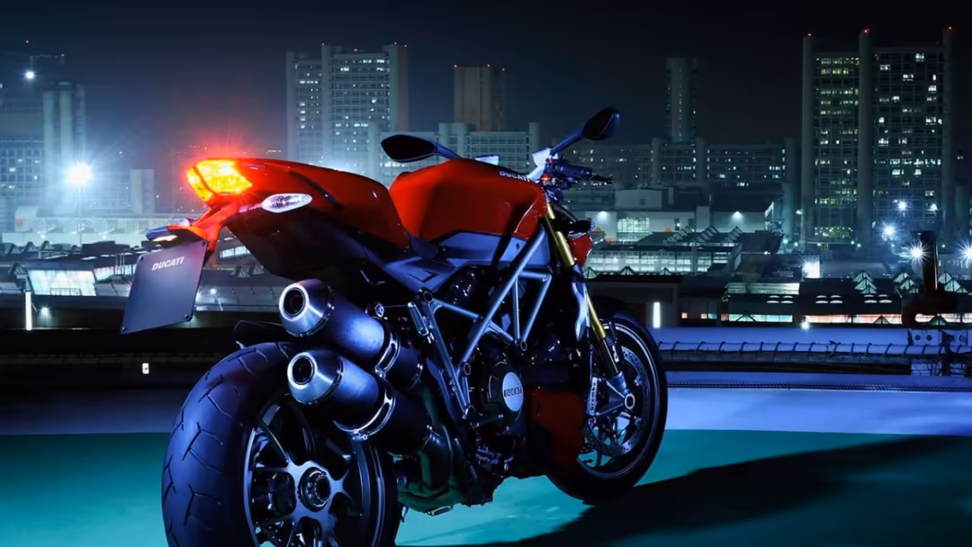 Red and black sport motorcycle with glowing neon lights parked against illuminated cityscape skyline at night with tall build