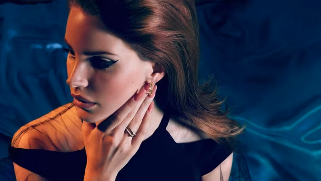 Woman with dark hair in profile, wearing orange and black, against deep blue cinematic background with dramatic lighting and