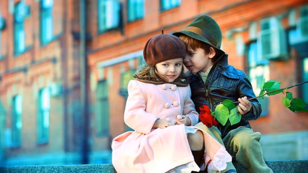 Two young children in vintage clothing sharing a romantic moment with a red rose against a brick building backdrop with turqu