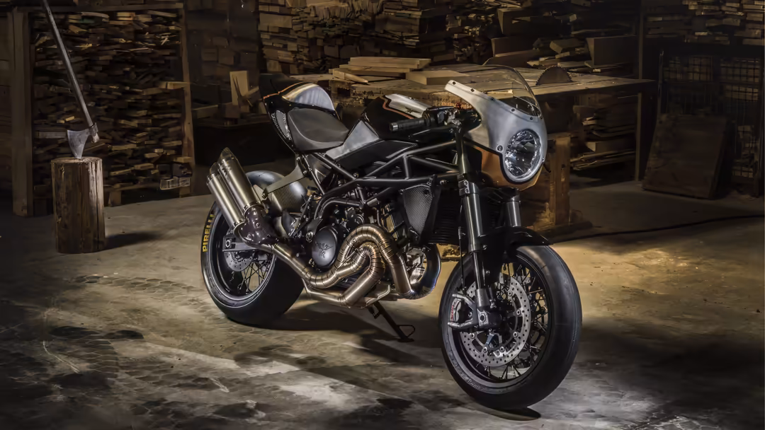 Custom motorcycle with polished engine and white fairing displayed in rustic industrial garage surrounded by wooden pallets a
