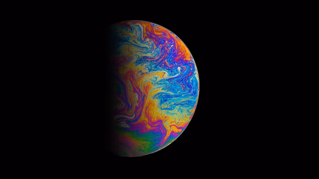 Vibrant planet with swirling multicolored atmosphere featuring blues, oranges, yellows, and magentas against a black space ba