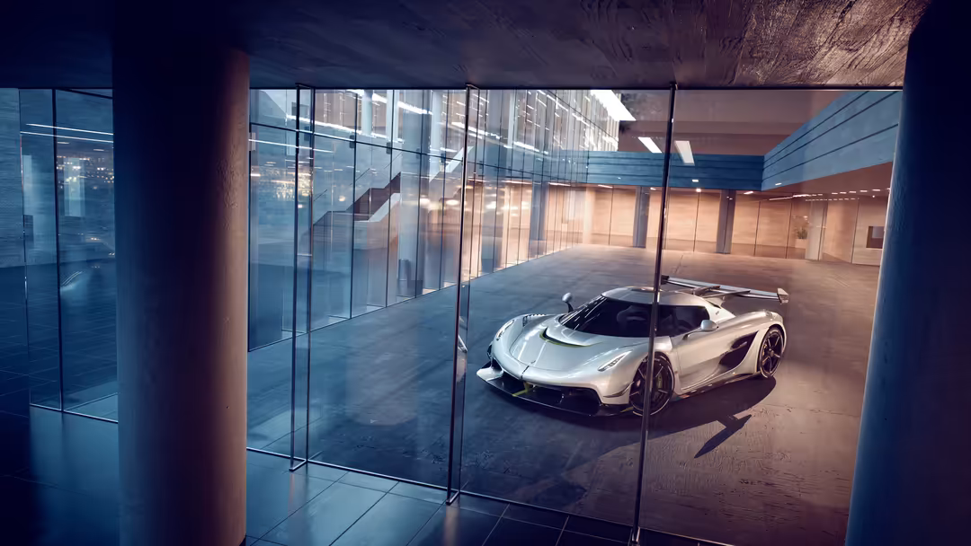 White Koenigsegg Jesko hypercar displayed in modern minimalist garage with glass walls and concrete floors